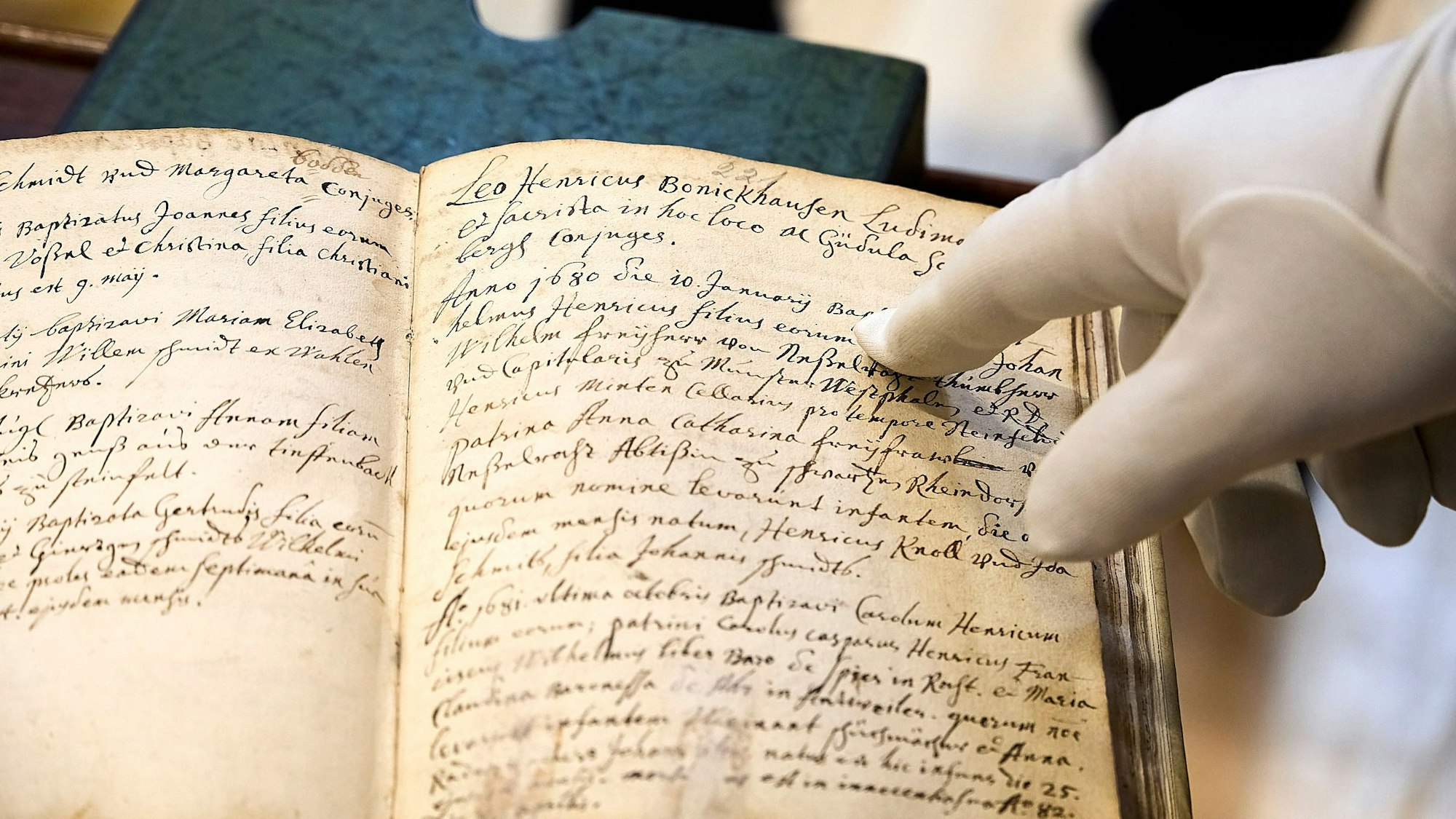 Eine Hand, die in einem weißen Handschuh steckt, zeigt auf einer Stelle in einer alten Schrift, die auf die Vorfahren von Gustave Eiffel verweist.