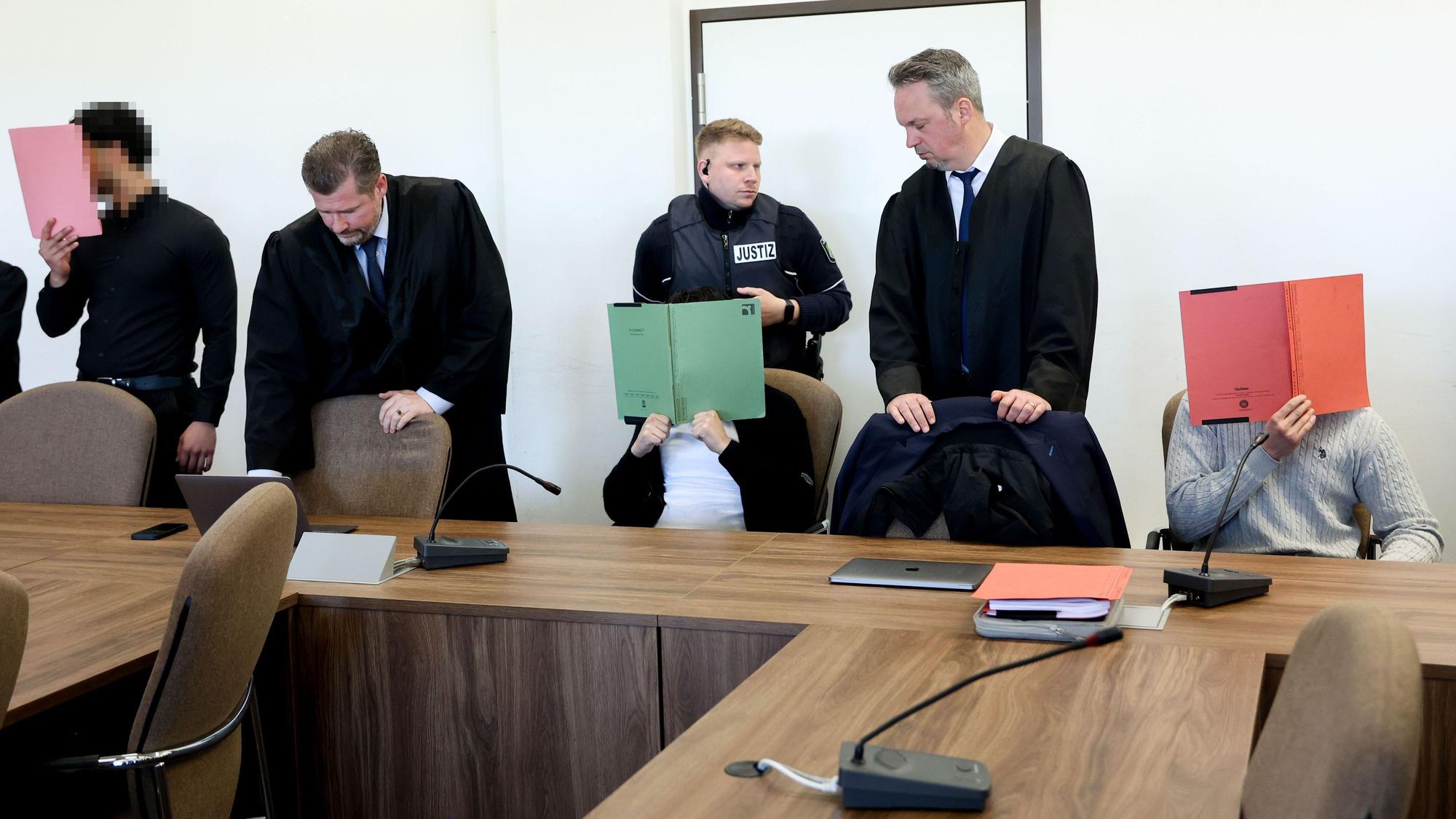 Die drei Angeklagten mit ihren Verteidigern beim Prozessauftakt im Kölner Landgericht.