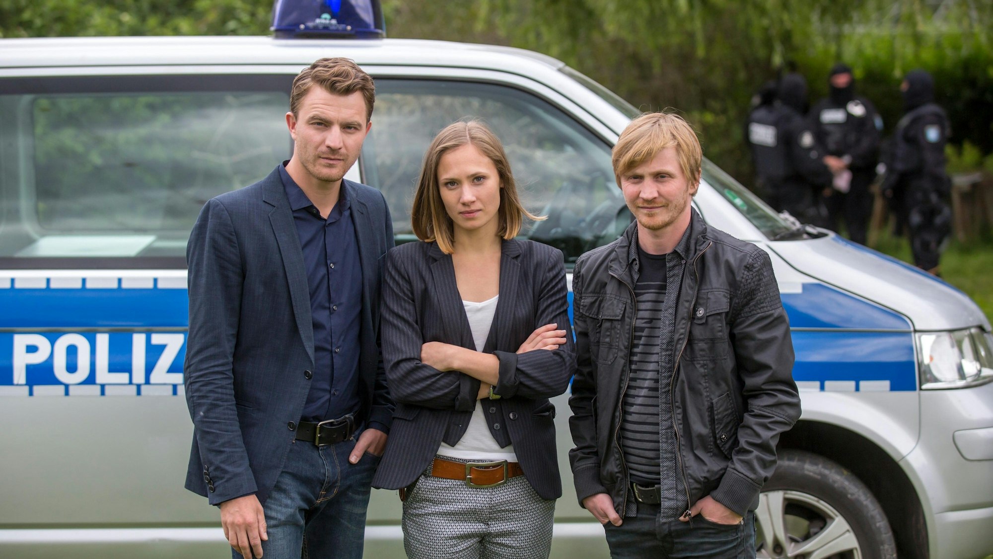 Die Schauspieler (l-r) Friedrich Mücke, Alina Levshin und Benjamin Kramme posieren vor einem Polizeiwagen.