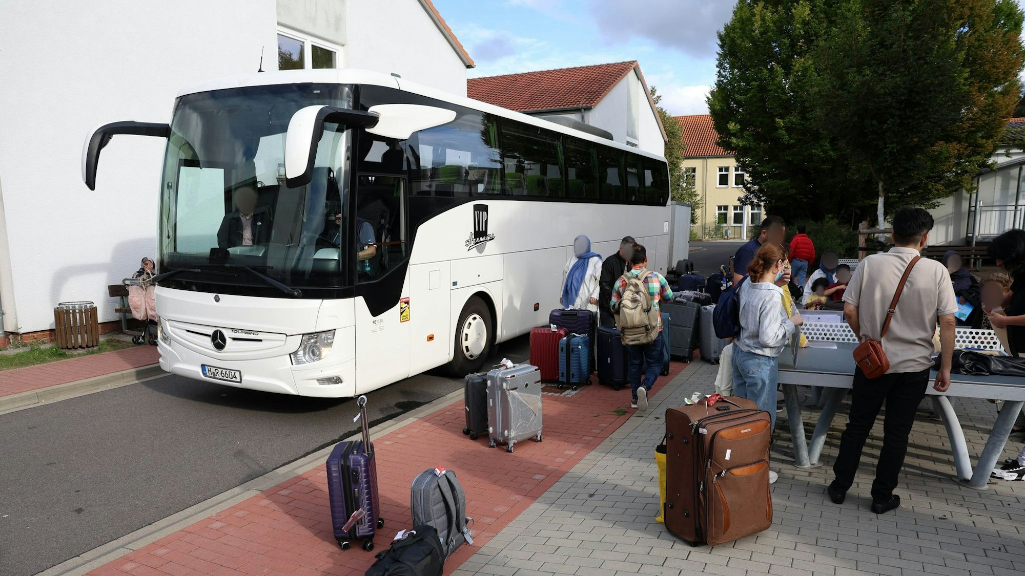 Flüchtlinge stehen in Deutschland neben einem Reisebus.