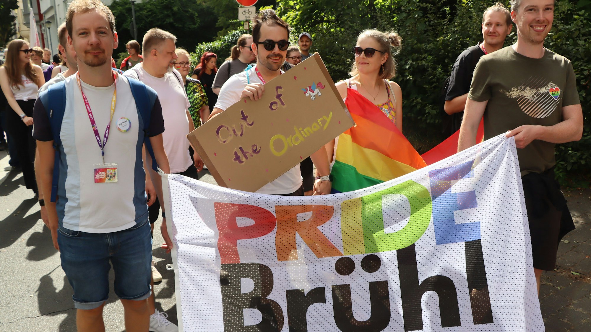 Zu sehen sind Demonstrationsteilnehmer, die ein buntes Banner mit der Aufschrift „Pride Brühl“ tragen.