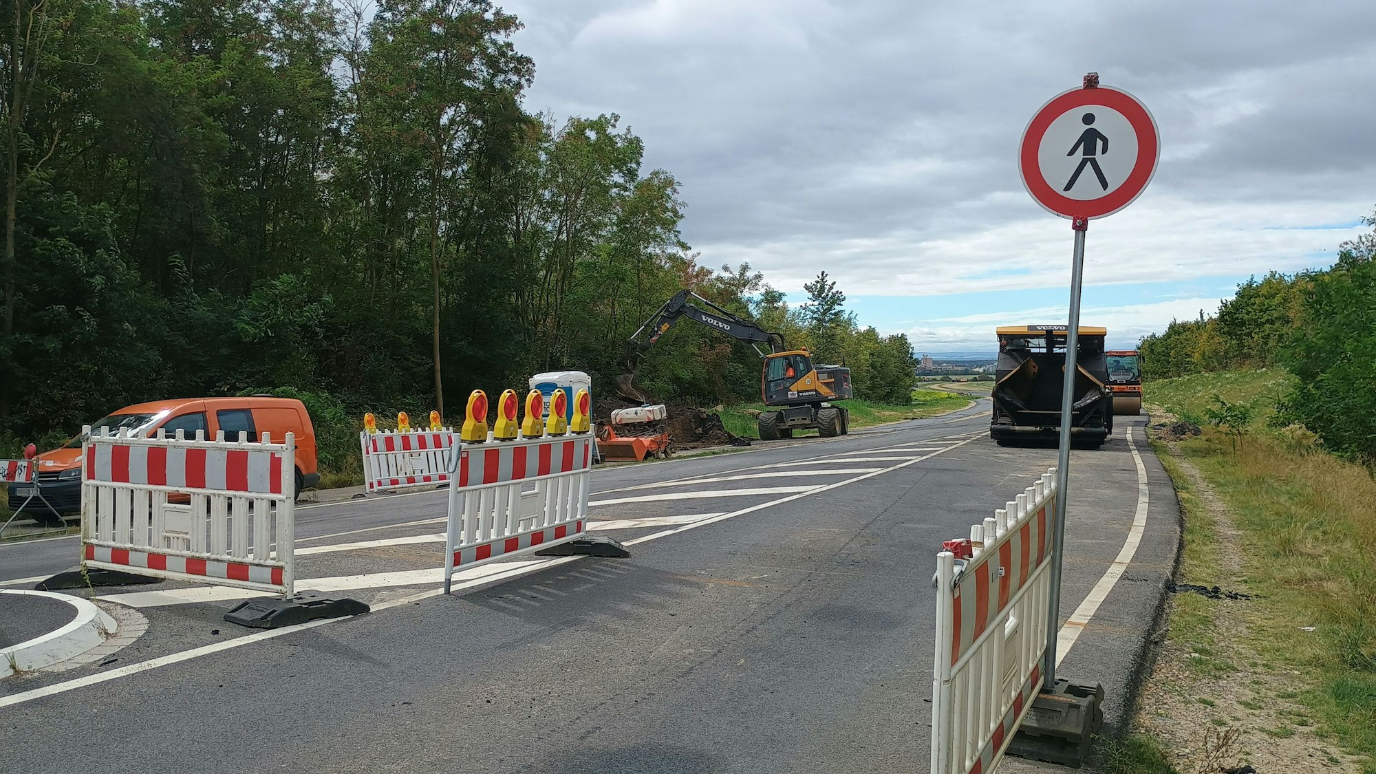 Aus Oberaußem kommend zeigen Absperrungen und ein Schild an, dass der Weg für Fußgänger gesperrt ist. Im Hintergrund Baufahrzeuge an der Straße.