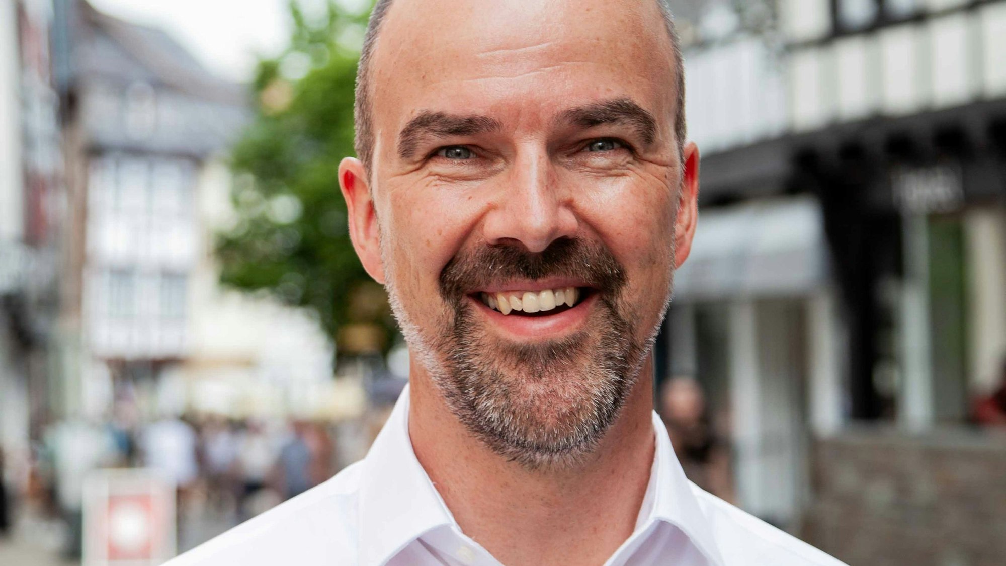 Guido Waters steht in der Bad Münstereifeler Kernstadt und trägt ein weißes Hemd.