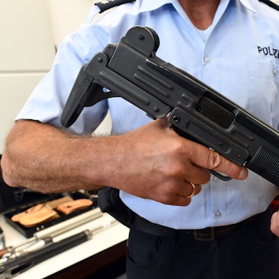 Ein Polizeibeamter hält eine Maschinenpistole vom Typ Uzi in den Händen.