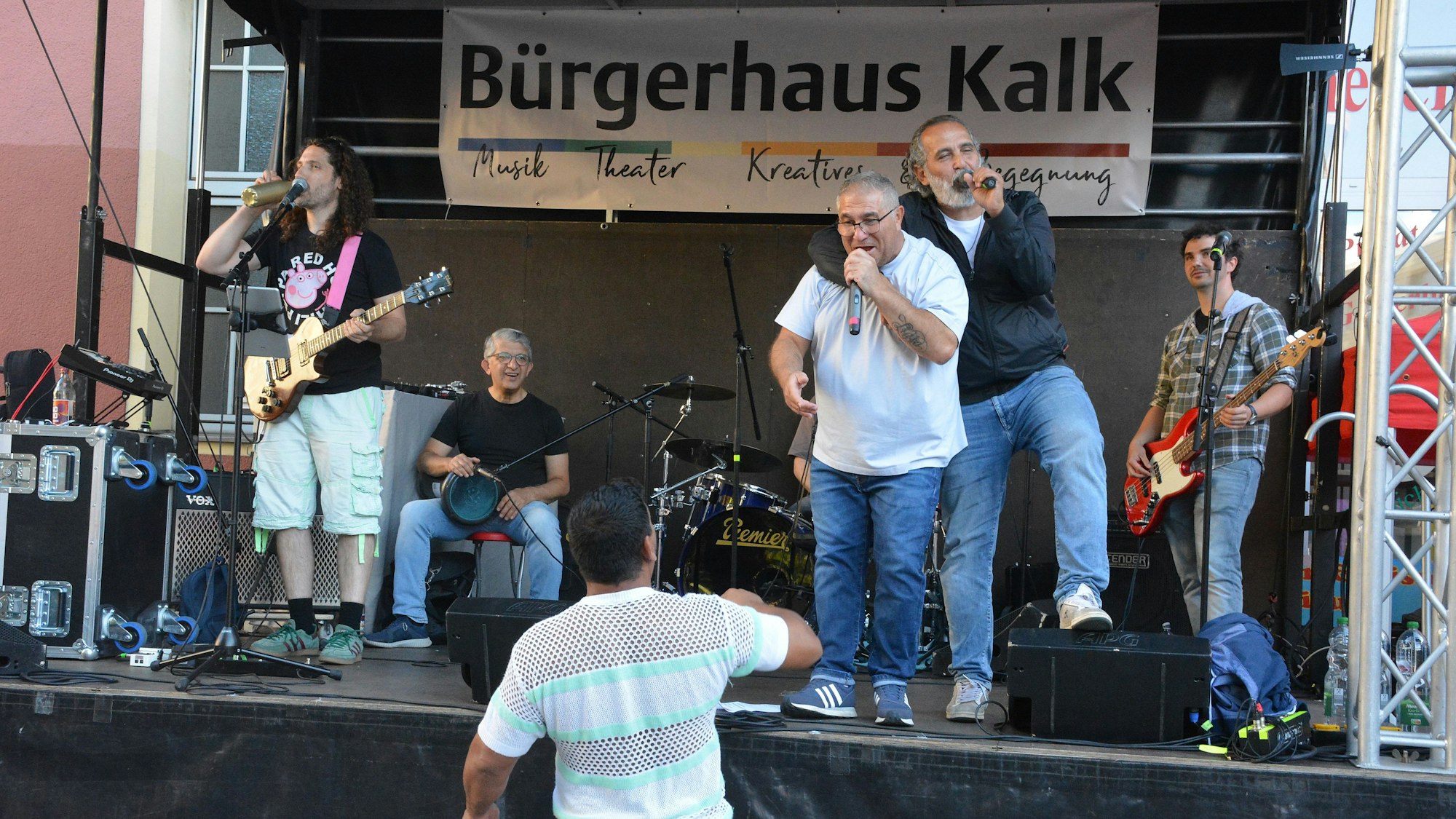 Ein Band, bestehend aus fünf Männern, performen ihre Lieder auf einer Bühne.