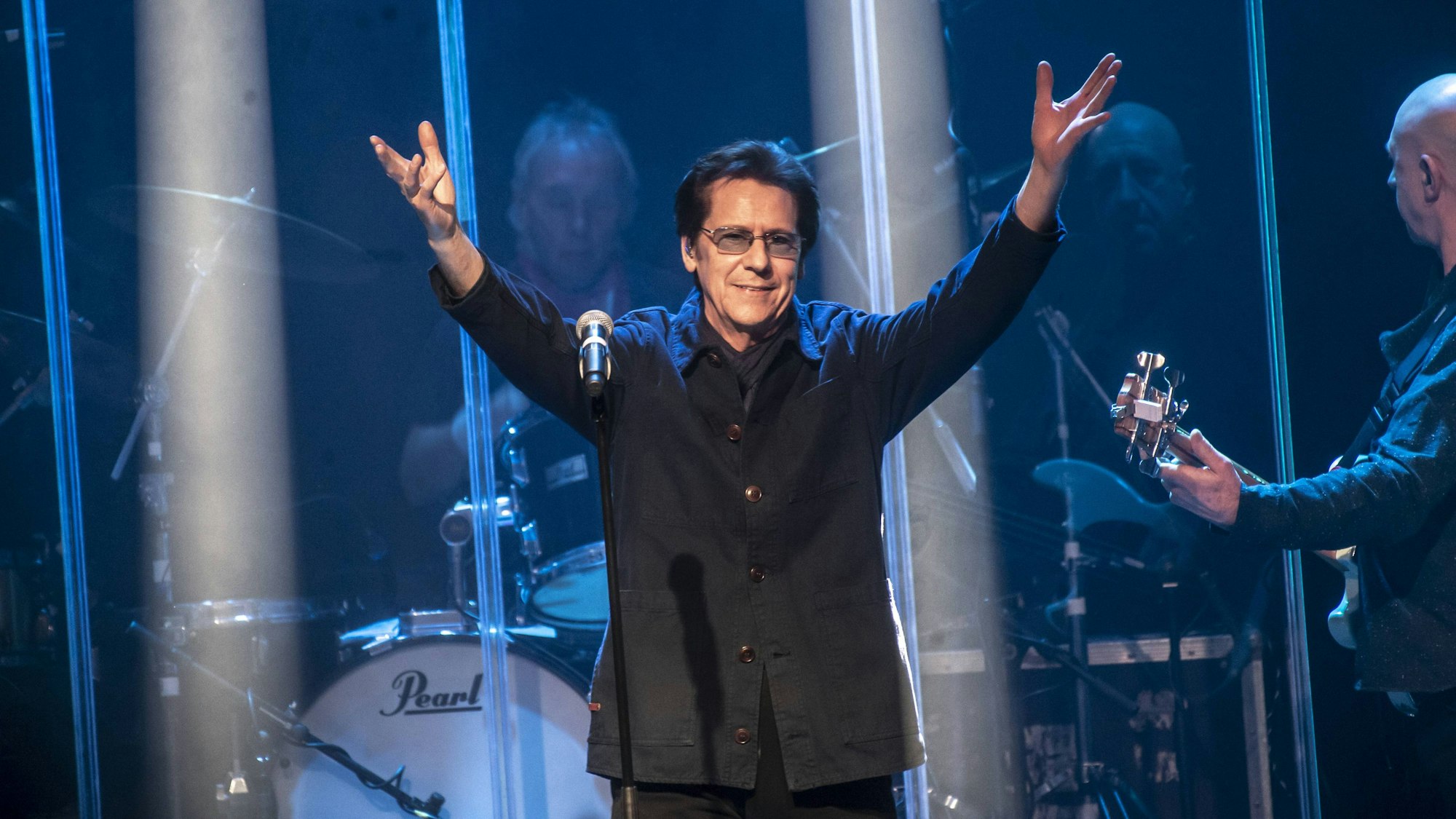 Shakin’ Stevens hebt die Arme auf der Bühne.