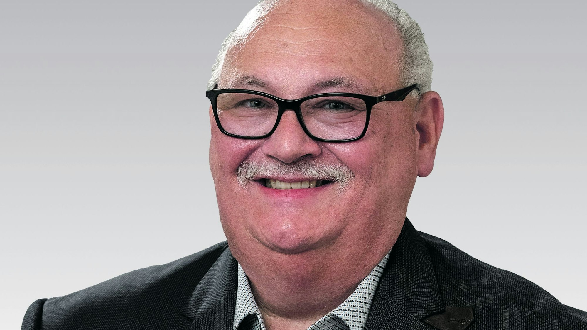 Edmund Daniel trägt Sakko und grün-kariertes Hemd.