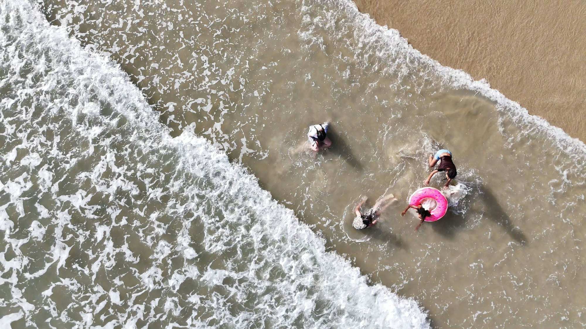 Glückliche Kinder, die zusammen im Meer spielen und einen schönen Sommertag am Strand genießen.