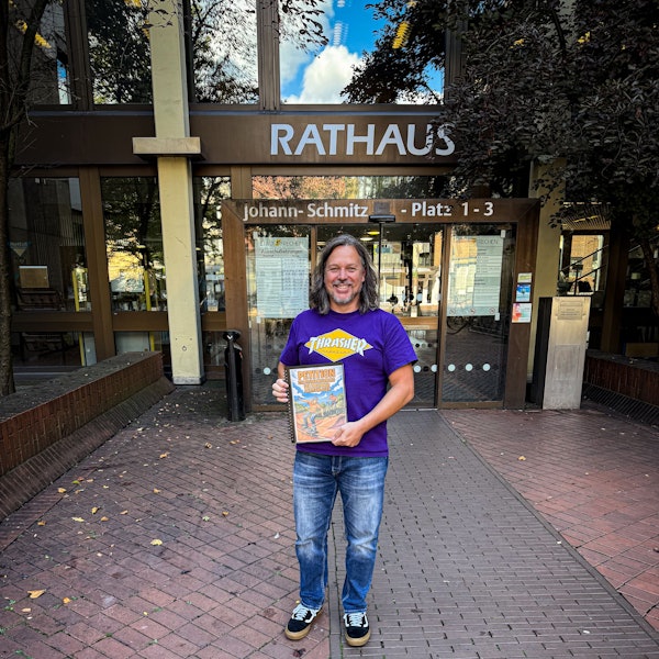 Auf dem Bild ist ein Mann vor dem Rathaus zu sehen, er hat eine Unterschriftenmappe in der Hand.