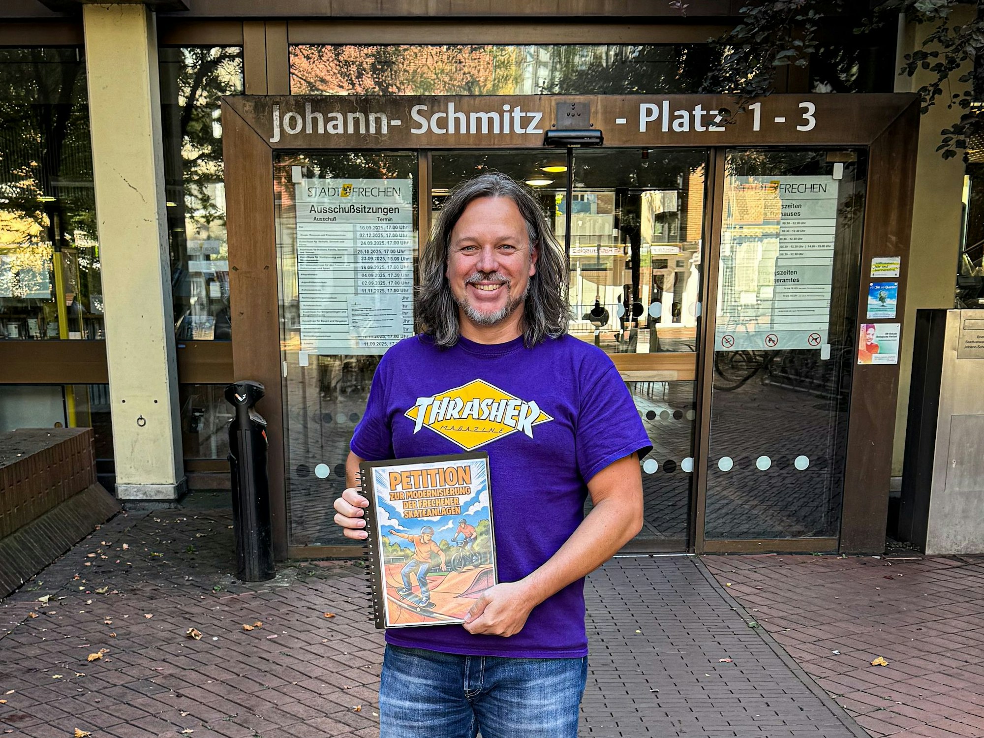 Auf dem Bild ist ein Mann mit einer Unterschriftensammlung vor dem Rathaus zu sehen.