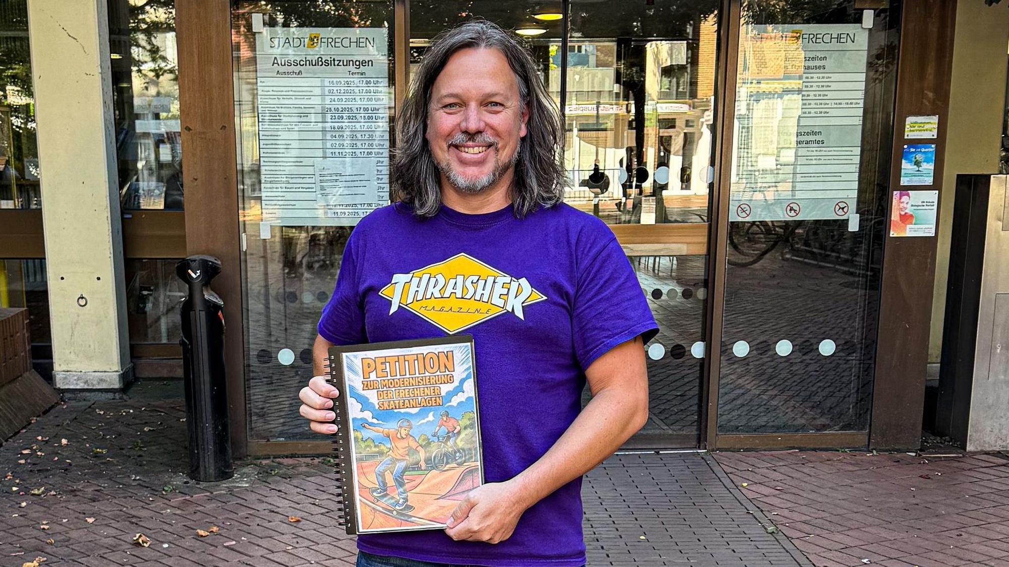 Auf dem Bild ist ein Mann mit einer Unterschriftenmappe vor dem Rathaus zu sehen.