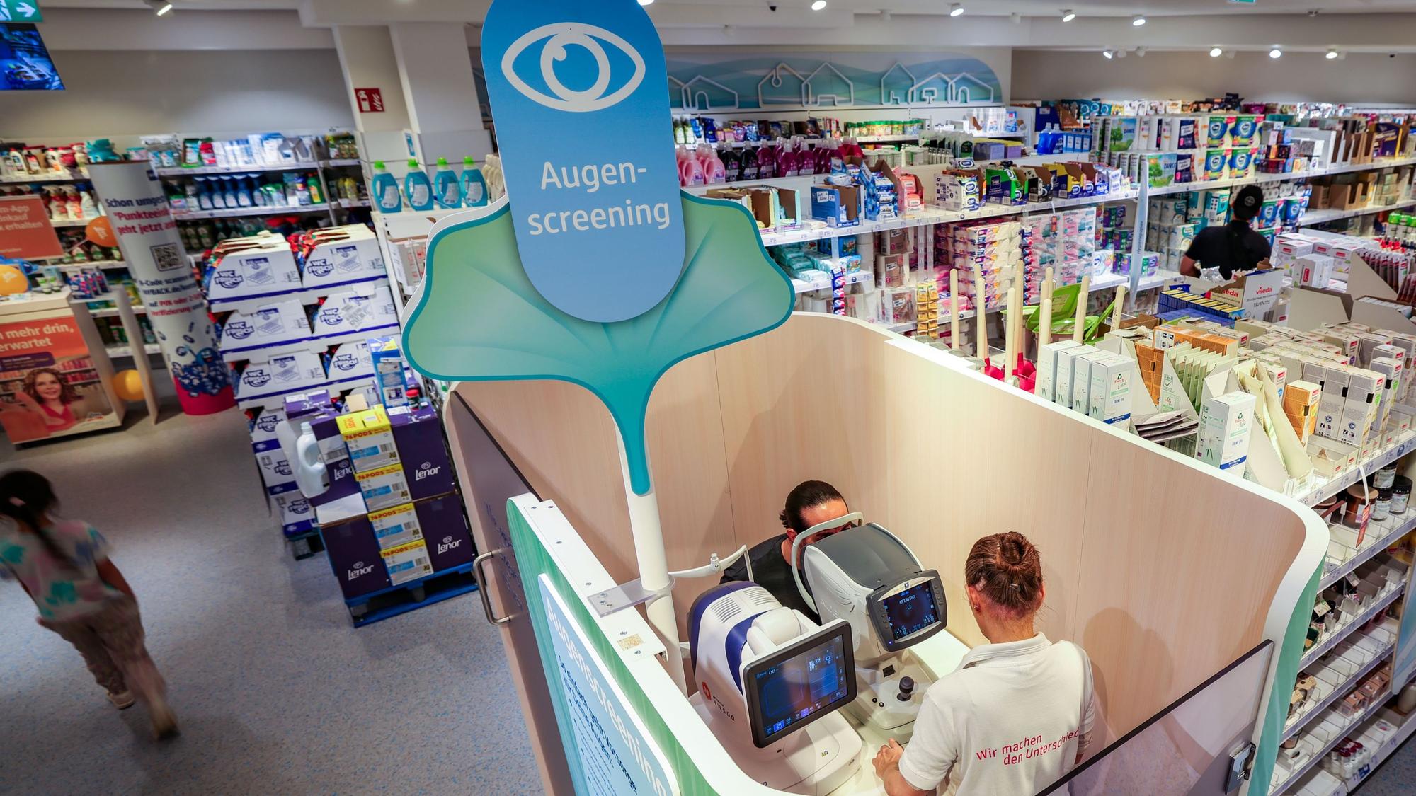 Eine Verkäuferin führt in einer dm-Filiale in Düsseldorf ein Augenscreening bei einem Kunden durch.