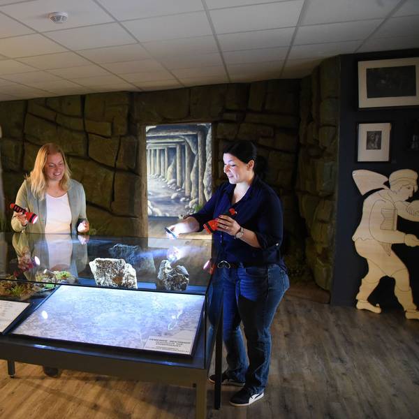Katja Wonneberger-Kühr (links) und Sarah-Sophie Riedel beleuchten mit Taschenlampen die Übersichtskarte im ersten der beiden Ausstellungsräume. Im weiteren Verlauf warten Grubenwerkzeuge, Erinnerungsstücke und auch Münzen aus Wildberger Silber auf die Besucher.
