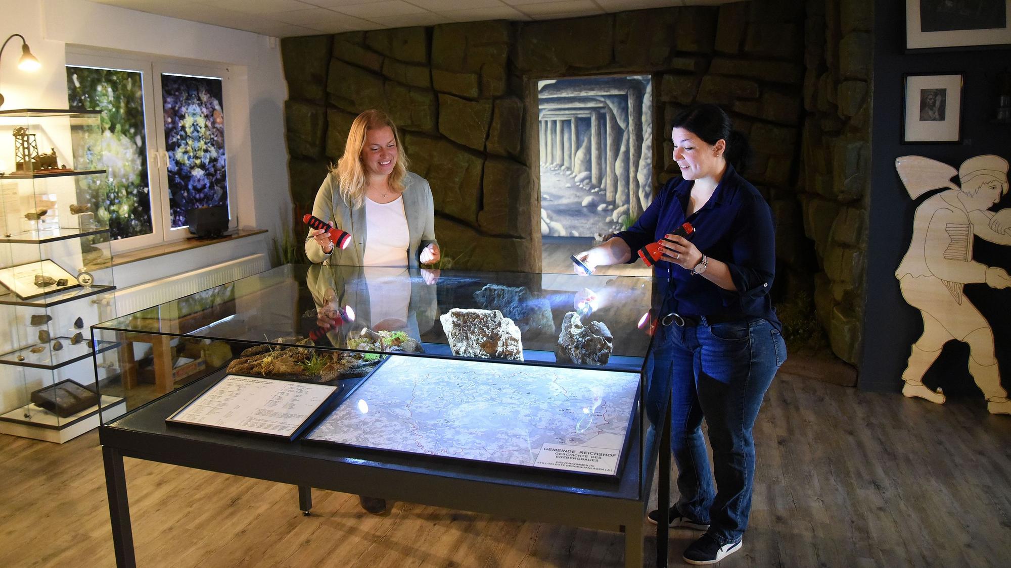 Katja Wonneberger-Kühr (links) und Sarah-Sophie Riedel beleuchten mit Taschenlampen die Übersichtskarte im ersten der beiden Ausstellungsräume. Im weiteren Verlauf warten Grubenwerkzeuge, Erinnerungsstücke und auch Münzen aus Wildberger Silber auf die Besucher.