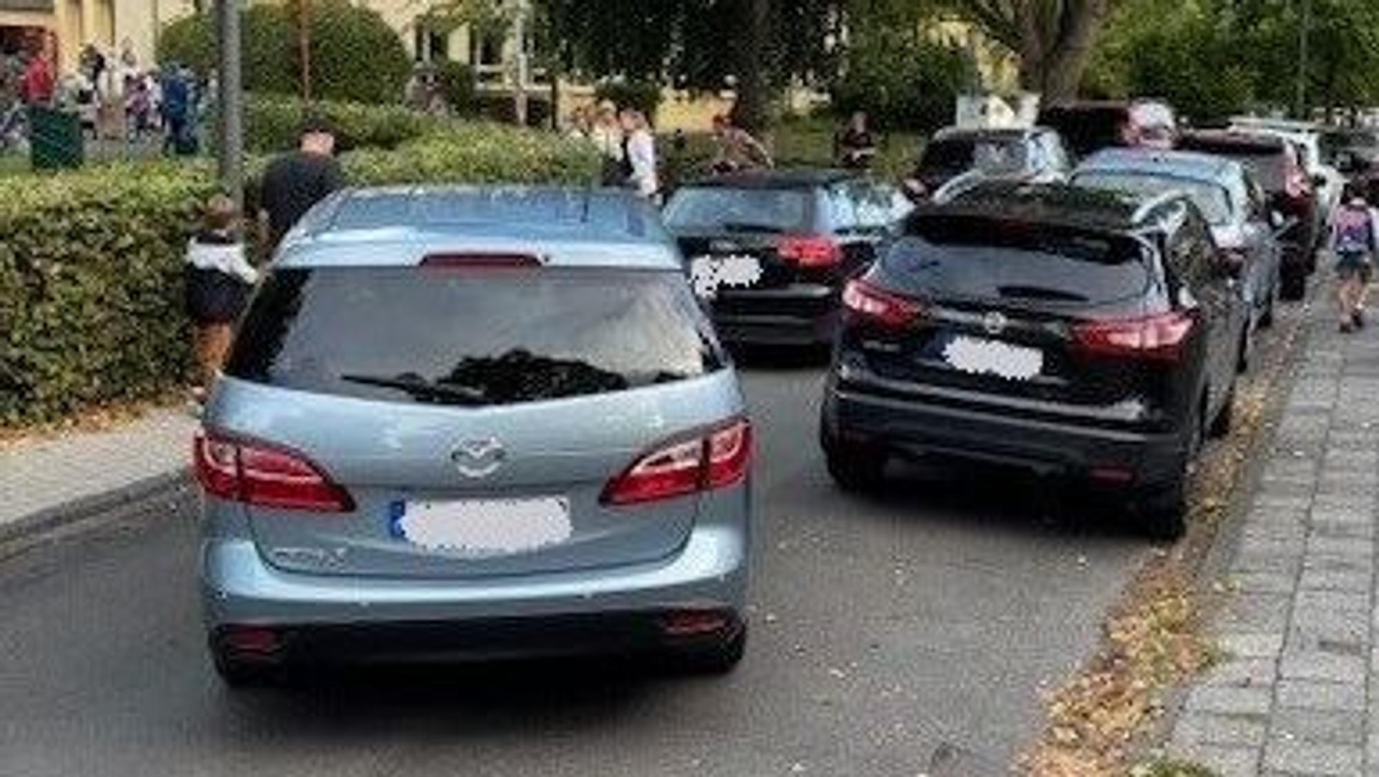 Parkende und fahrende Autos verstopfen eine kleine Straße.