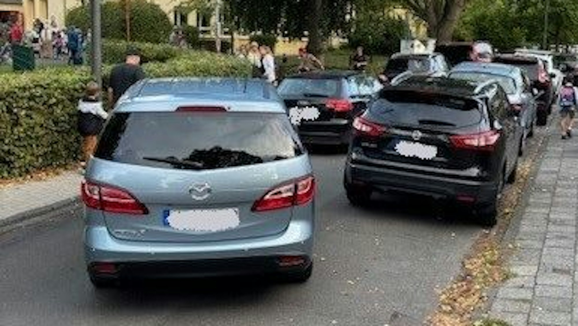 Parkende und fahrende Autos verstopfen eine kleine Straße.