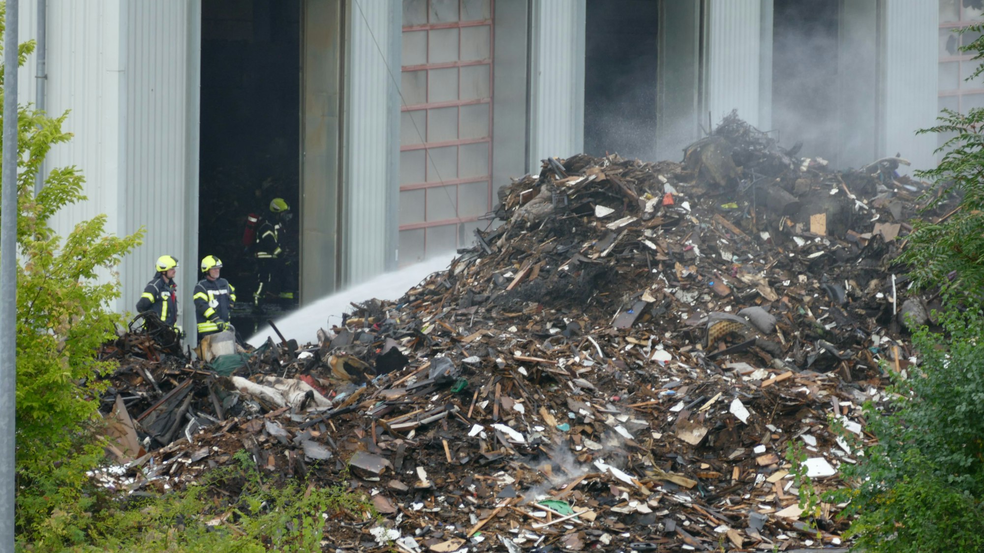 Die Feuerwehr schichtete den brennenden Sperrmüll vor der Halle in Troisdorf auf, um ihn draußen ablöschen zu können.