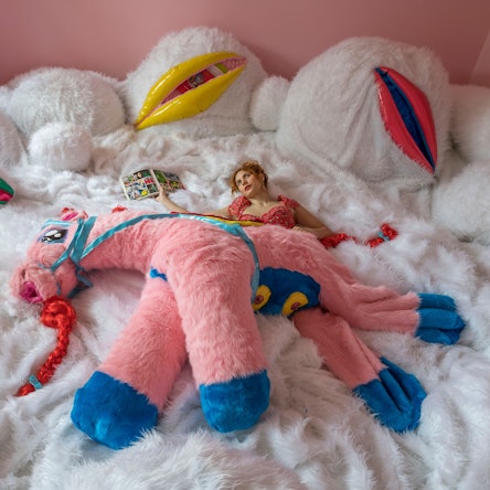 Eine junge Frau liegt in einer Plüschtierlandschaft.