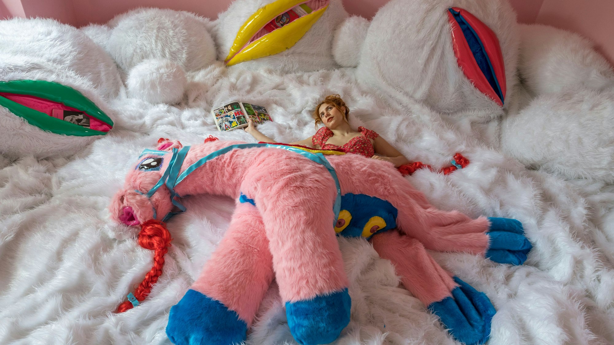 Eine junge Frau liegt in einer Plüschtierlandschaft.