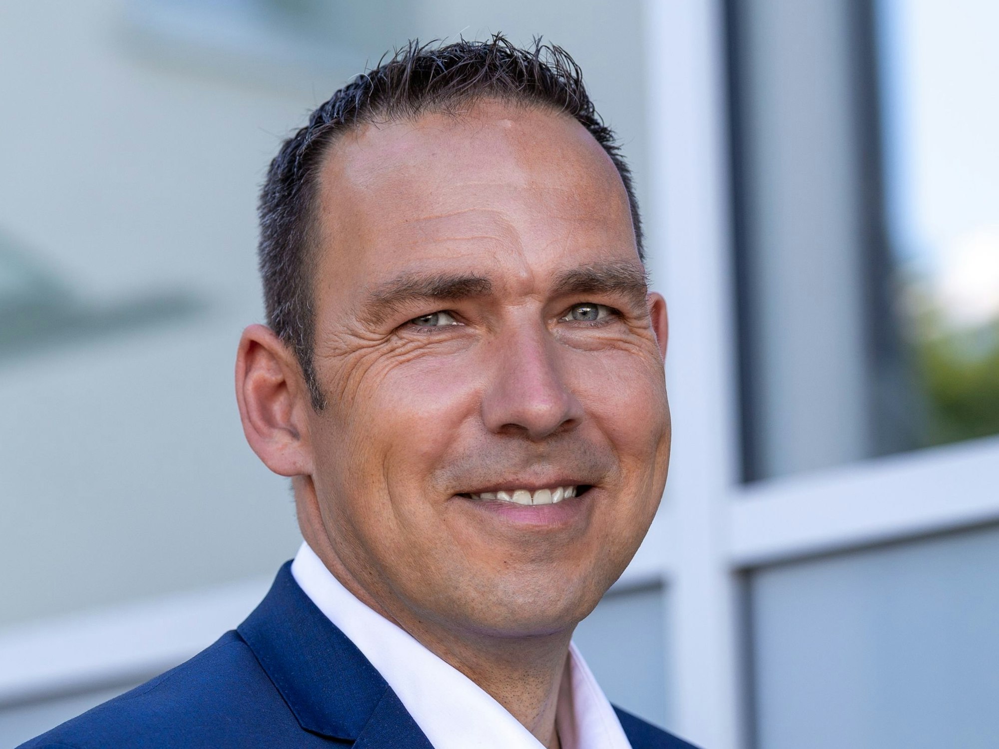 Dino Steuer trägt Anzug und lächelt.