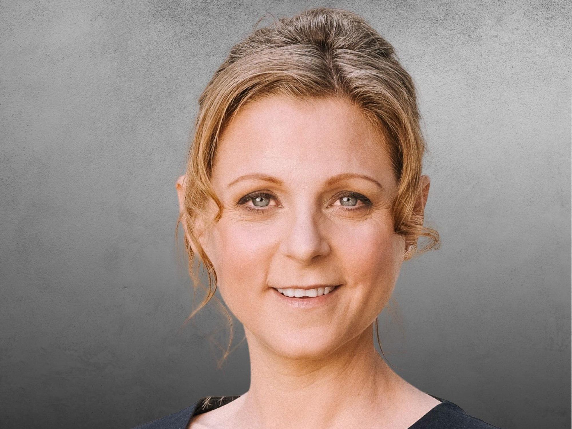 Myriam Kemp lächelt vor einem neutralen Hintergrund.