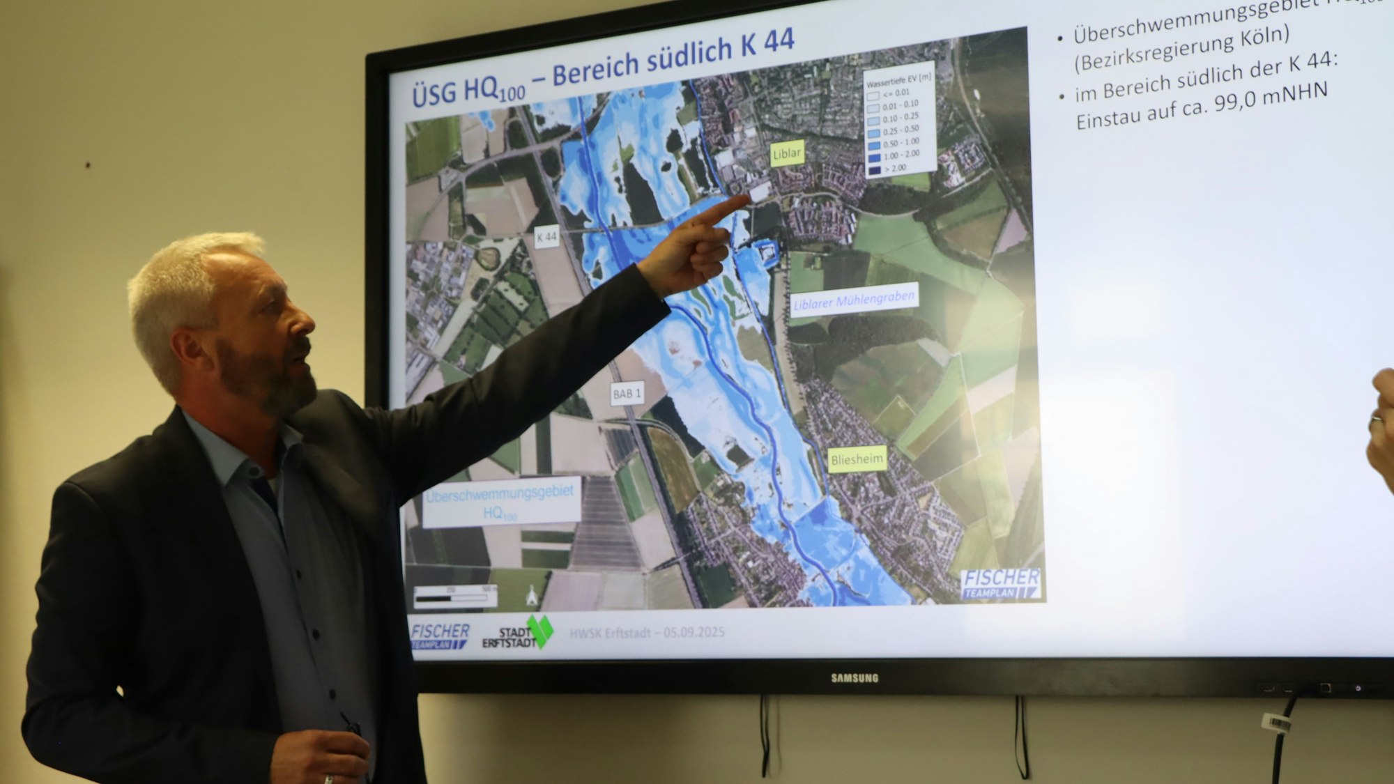 Das Bild zeigt Dirk Schulz, der mit dem Finger auf einen Bildschirm zeigt. Auf dem Bildschirm ist eine Karte der Stadt zu sehen.