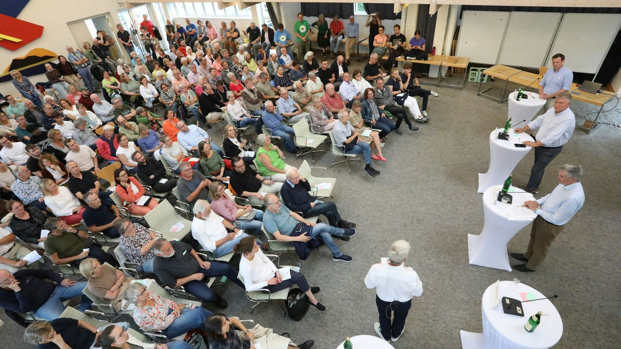 Ein Saal mit vielen Menschen, die auf Stühlen sitzen.
