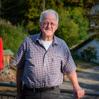 Ein Mann im Karohemd lächelt in die Kamera.