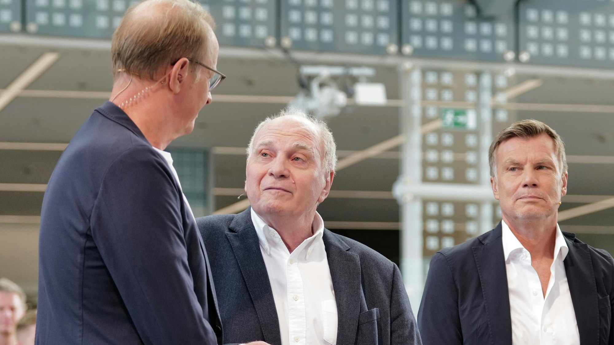 dpatopbilder - 07.09.2025, Bayern, München: Die Moderatoren Florian König (l) und Thomas Helmer (r) unterhalten sich mit FC Bayern Ehrenpräsident Uli Hoeneß während der Jubiläumssendung 30 Jahre "Doppelpass", auf der Sendefläche im Hotel Hilton am Flughafen. Foto: Uwe Lein/dpa +++ dpa-Bildfunk +++