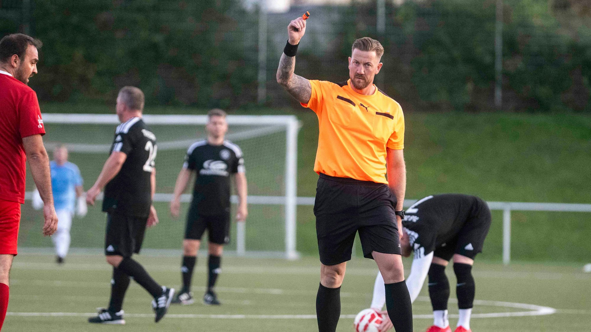 Der Unparteiische hält nach einem Pfiff seine Pfeife in die Luft.