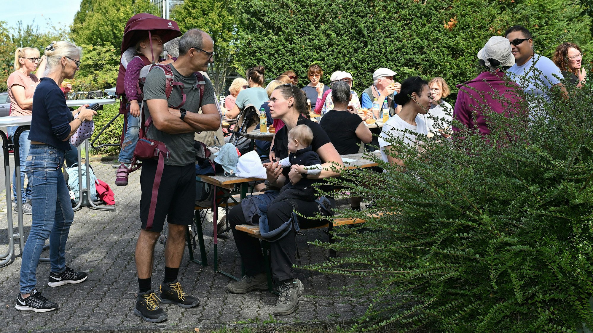 Eine Gruppe Menschen sitzt auf Bänken und isst.