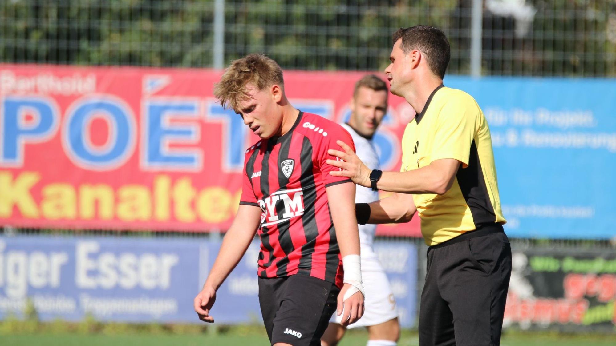 Spieler Rick sieht enttäuscht aus, der Schiedsrichter redet ihm gut zu.