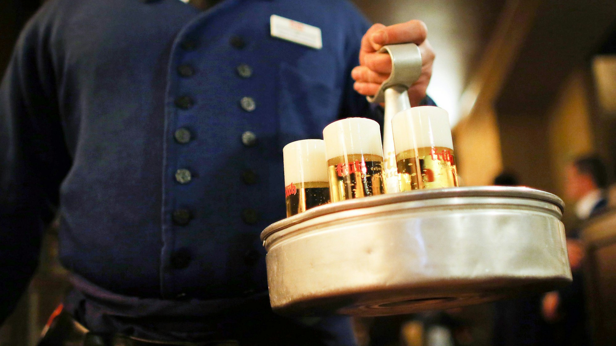 Ein Köbes (Kellner) trägt im Brauhaus Früh am Dom Kölsch-Bier. Das Oberlandesgericht Düsseldorf verhandelt über die Einsprüche von drei Kölsch-Brauereien gegen Bierkartell-Bußgelder der Kartellamtes. Das Bundeskartellamt hatte wegen verbotener Preisabsprachen im Rahmen des «Bierkartells» hohe Geldbußen gegen die Kölner Brauereien Früh, Gaffel und Erzquell verhängt. Dagegen haben die Brauereien Einspruch eingelegt. +++ dpa-Bildfunk +++