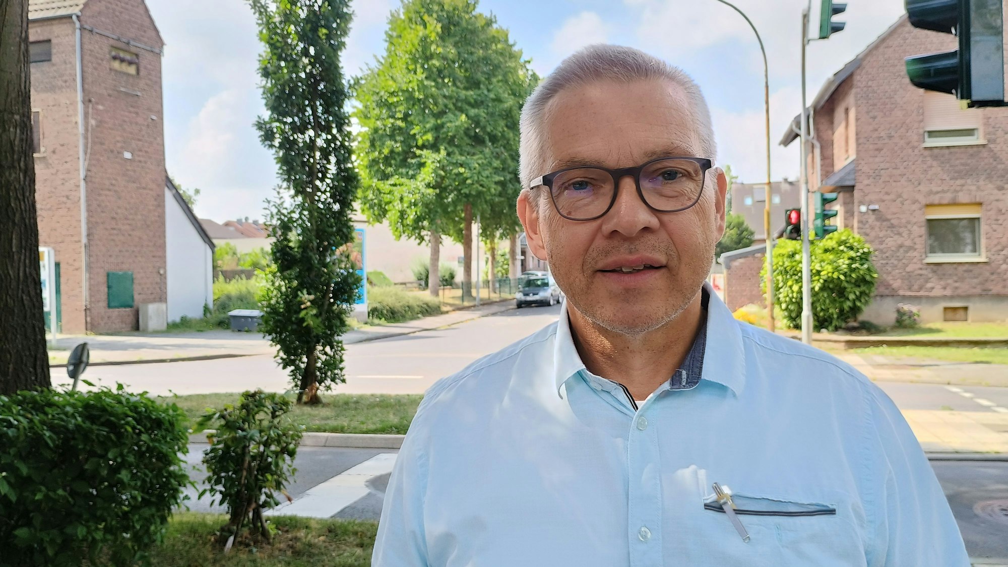 Das Bild zeigt den Ortsbürgermeister an der Fußgängerampel. Er trägt ein hellblaues Hemd und eine Brille.