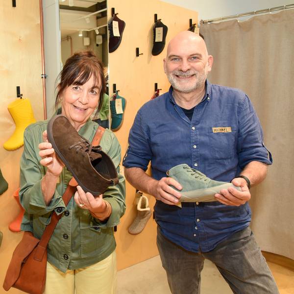 Michael Hiß (Nordwolle) und Barbara Papst von Wildling Shoes halten Schuhe in einem Showroom in den Händen.