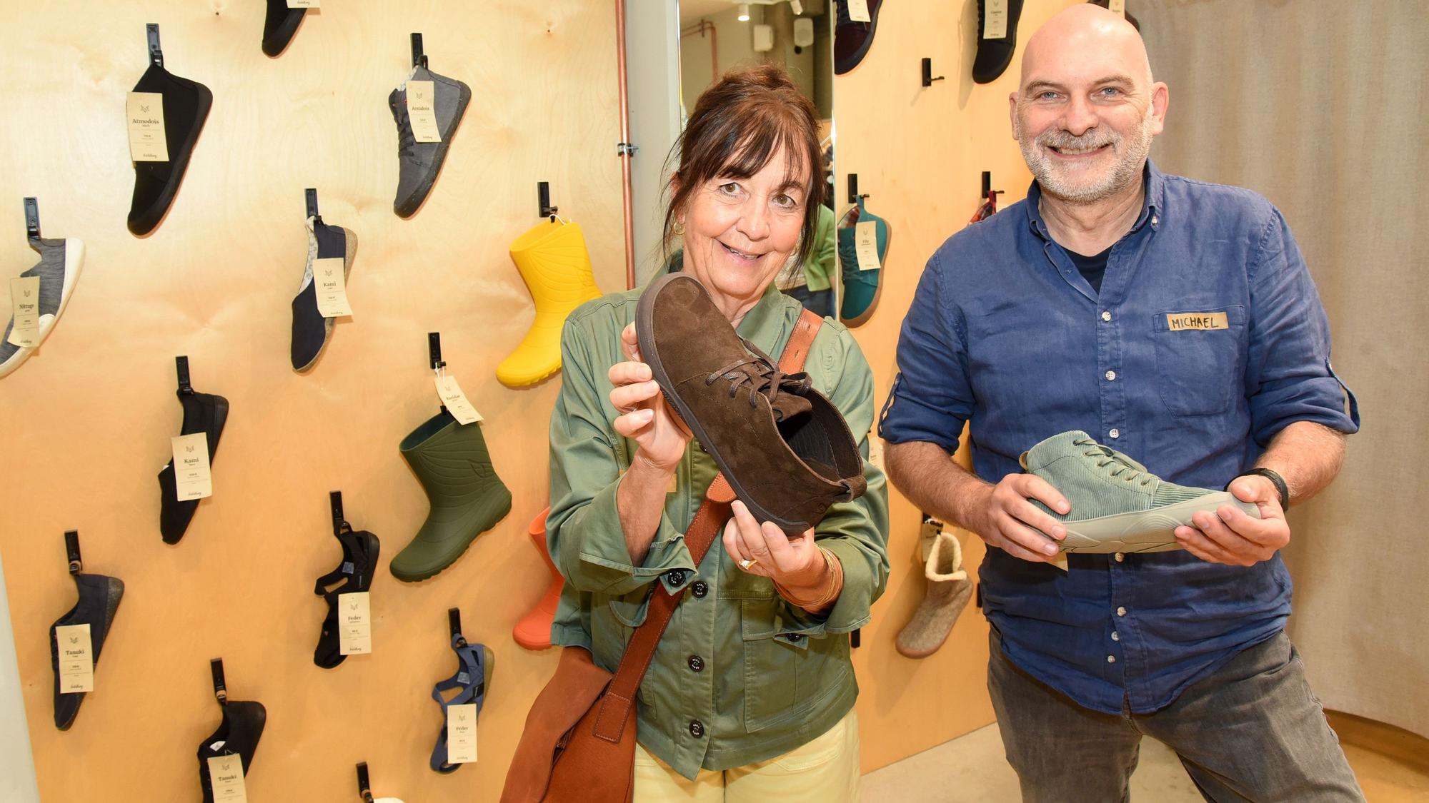 Michael Hiß (Nordwolle) und Barbara Papst von Wildling Shoes halten Schuhe in einem Showroom in den Händen.