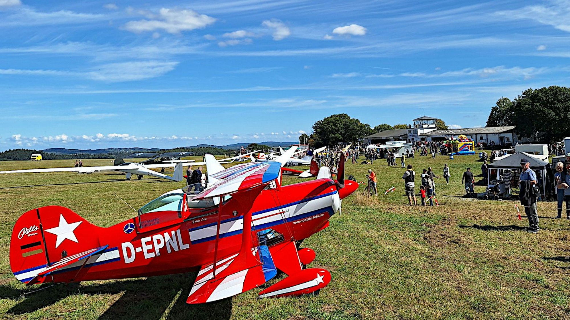 Ein Blick über den Flugplatz in Wershofen, im Vordergrund steht ein knallrotes Flugzeug.