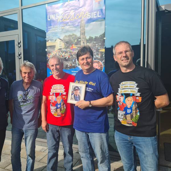 Fünf Männer stehen vor einer Glastür. Einer hält ein Bild.