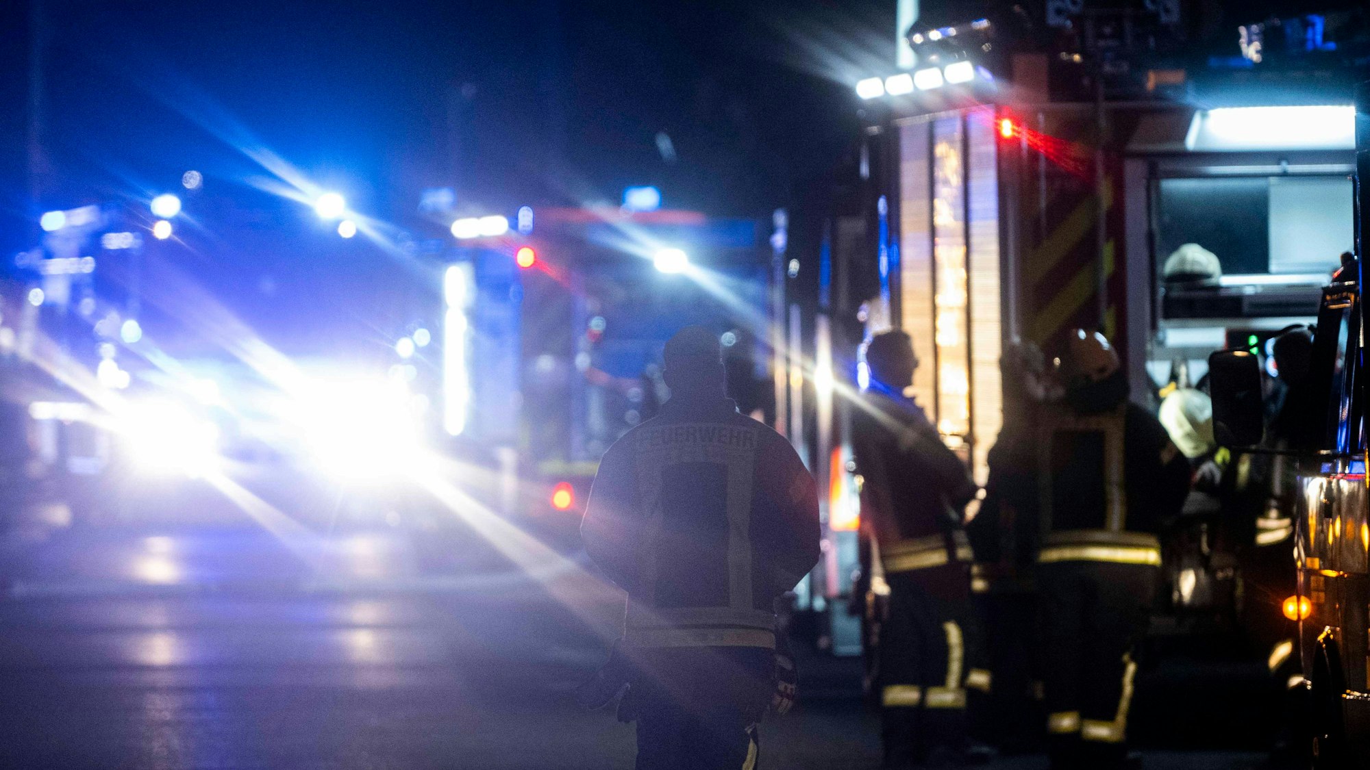 Das Symbolbild zeigt Feuerwehrfahrzeuge und Feuerwehrleute bei einem nächtlichen Einsatz.