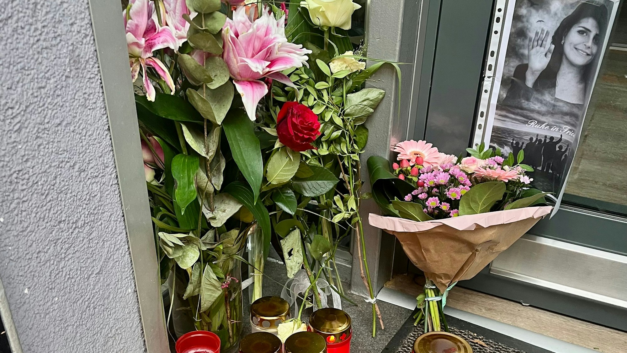 Kerzen stehen vor dem Eingang eines Friseursalons.