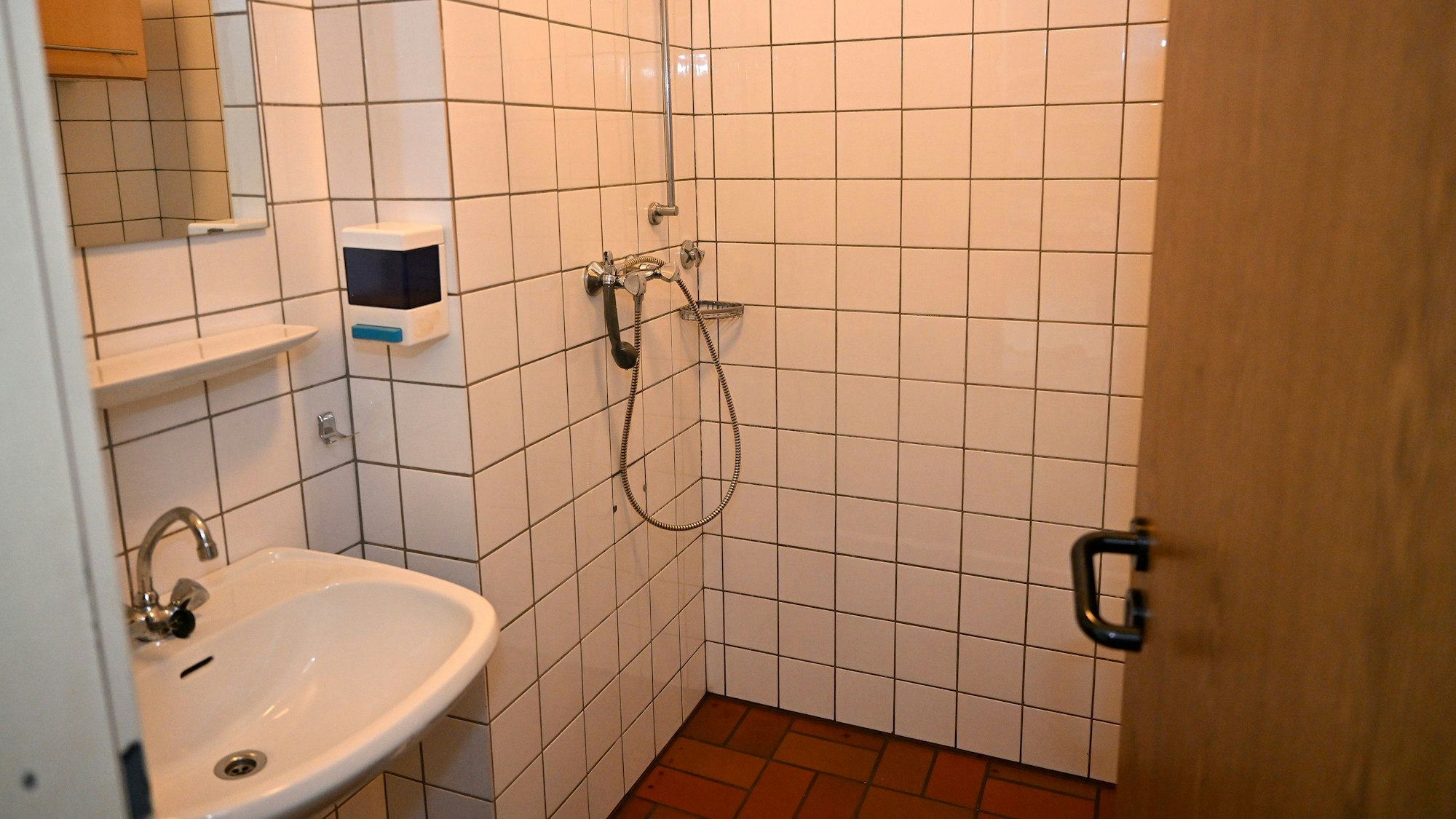 Eine etwas in die Jahre gekommene Dusche mit weißen Kacheln.