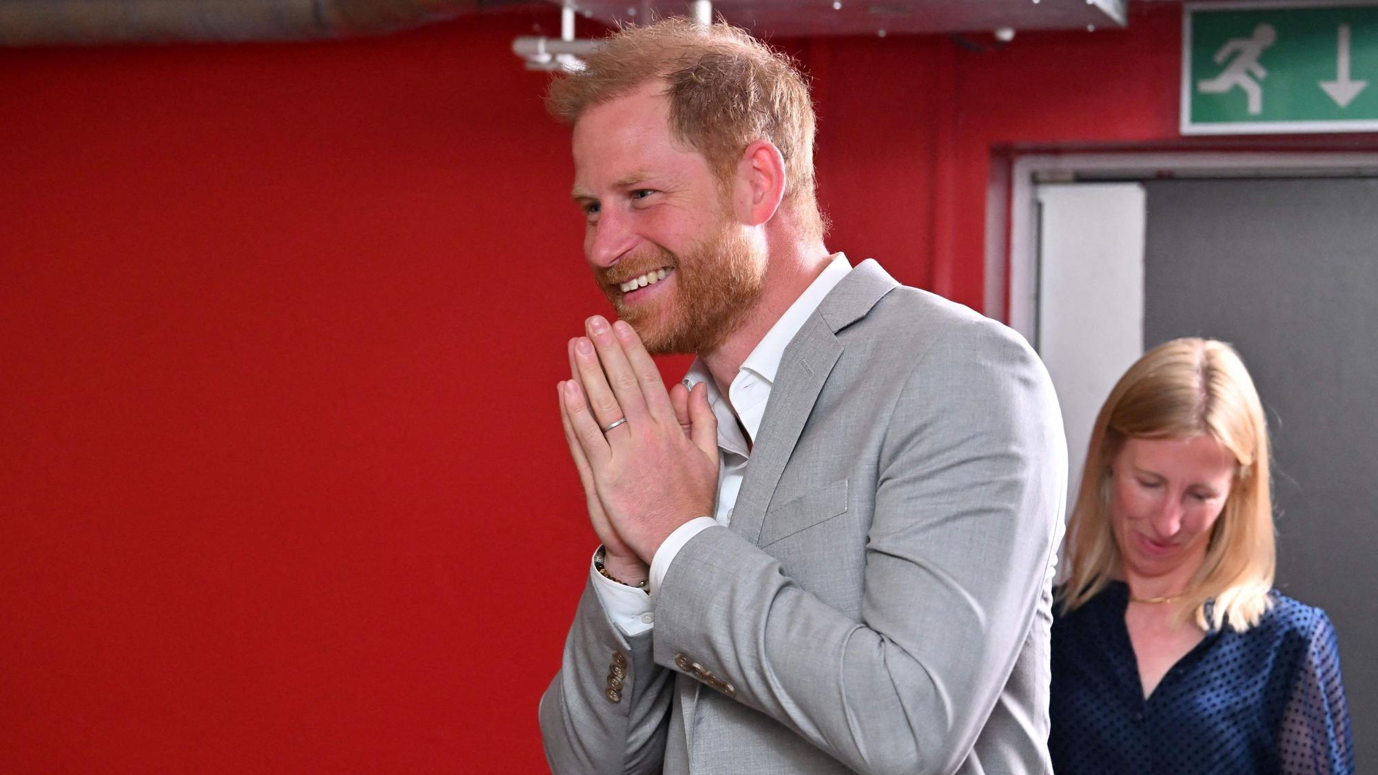 Prinz Harry faltet die Hände und lacht.