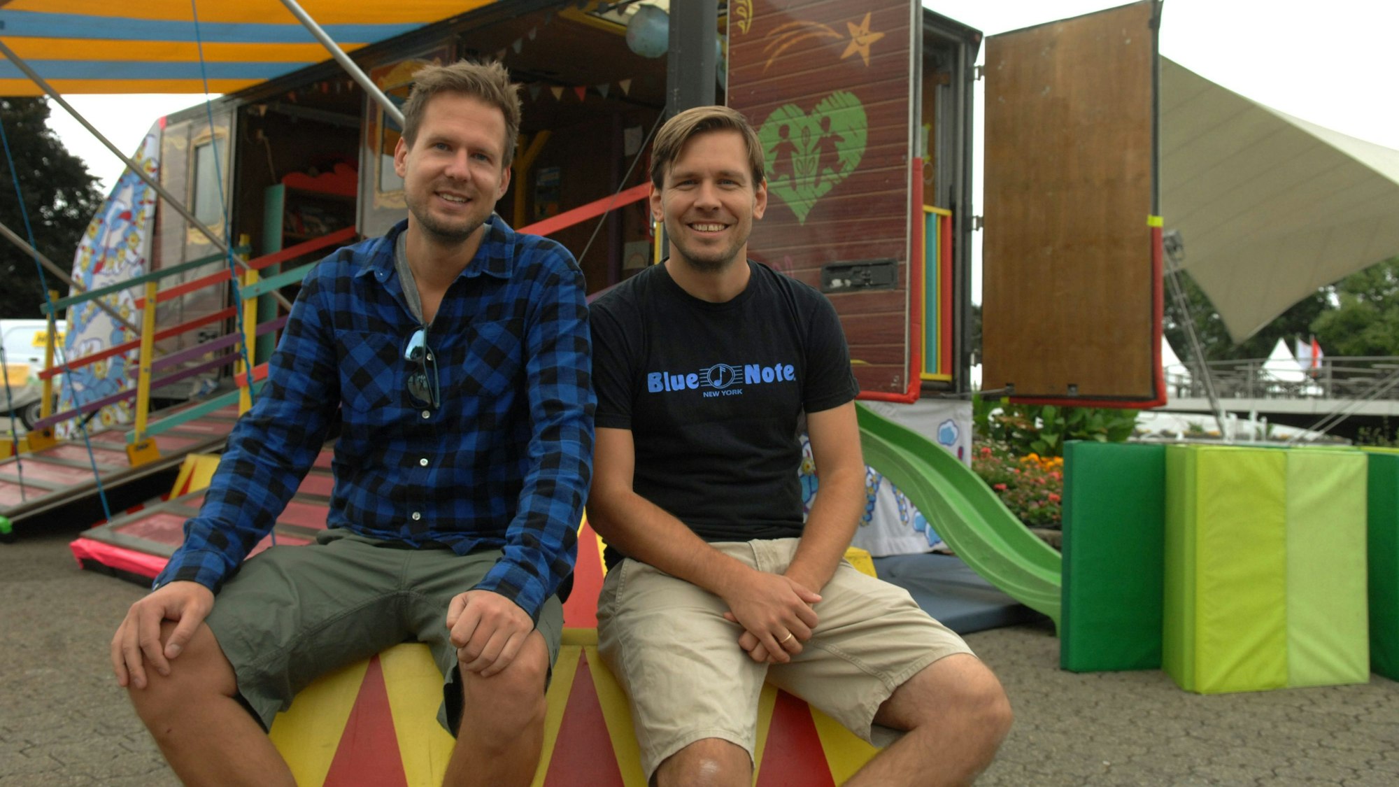 Das Familienfest Vivawest im Tanzbrunnen lockt mit Kölschen Bands, zum Beispiel mit Miljö, hier sind Mike Kremer und Max Eumann der Band zu sehen, die vor einem bunten Wagen sitzen. (Archivbild)