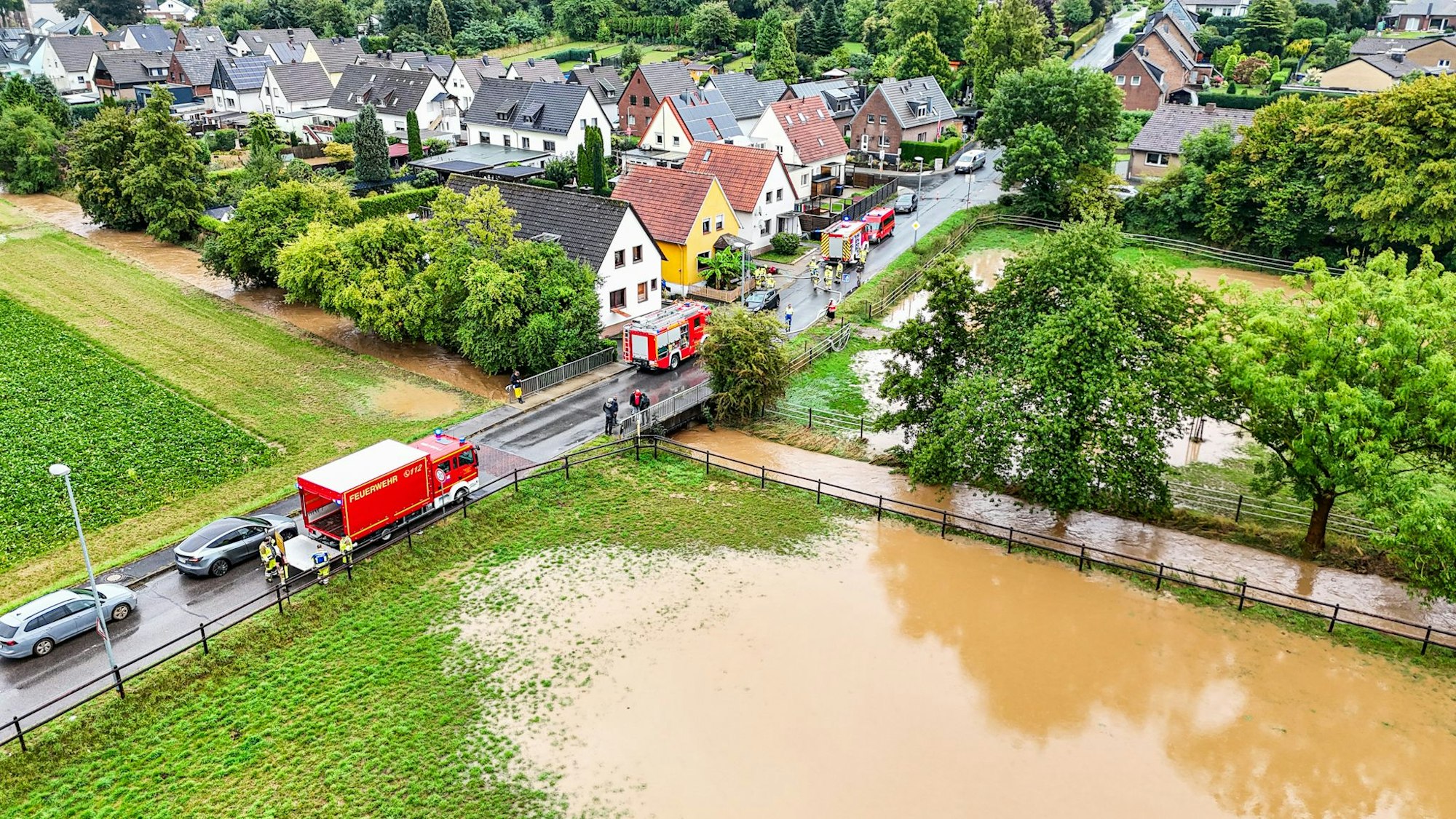 Zu sehen ist ein über die Ufer getretener Bach aus der Luft.