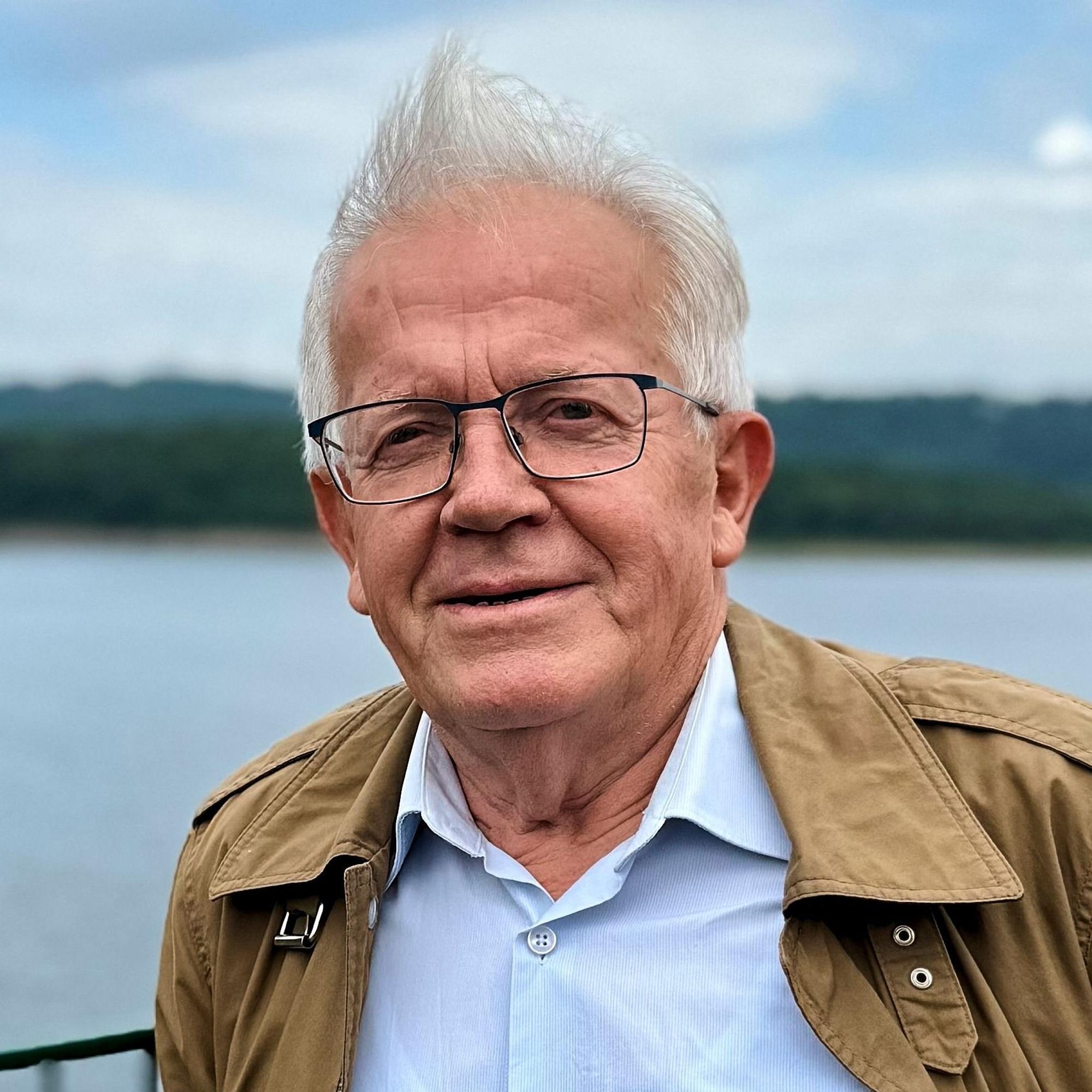 Hubert Kast steht vor einem unscharf gestellten Gewässer.