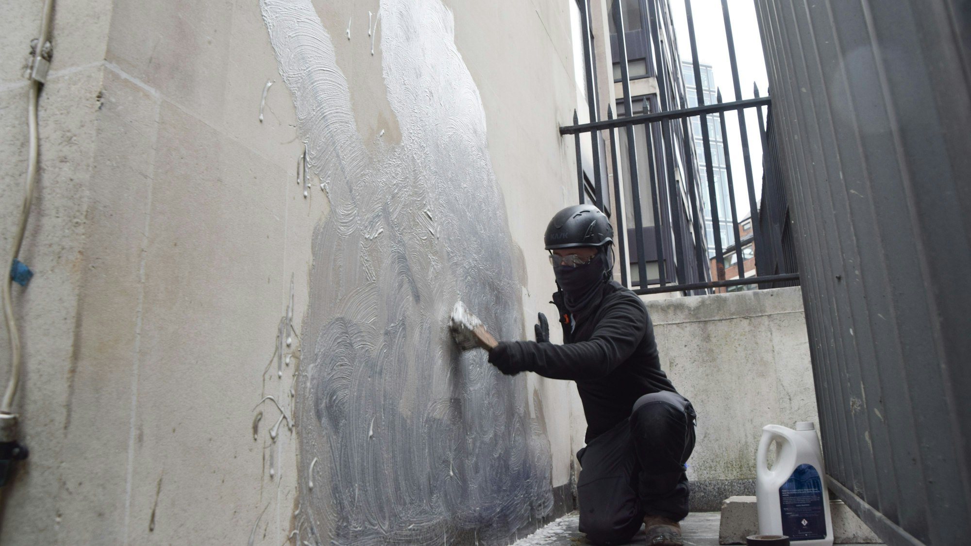 Eine Person schrubbt das neueste Kunstwerk des britischen Künstlers Banksy an den Royal Courts of Justice ab, das einen Richter zeigt, der einen Demonstranten mit einem Hammer schlägt.