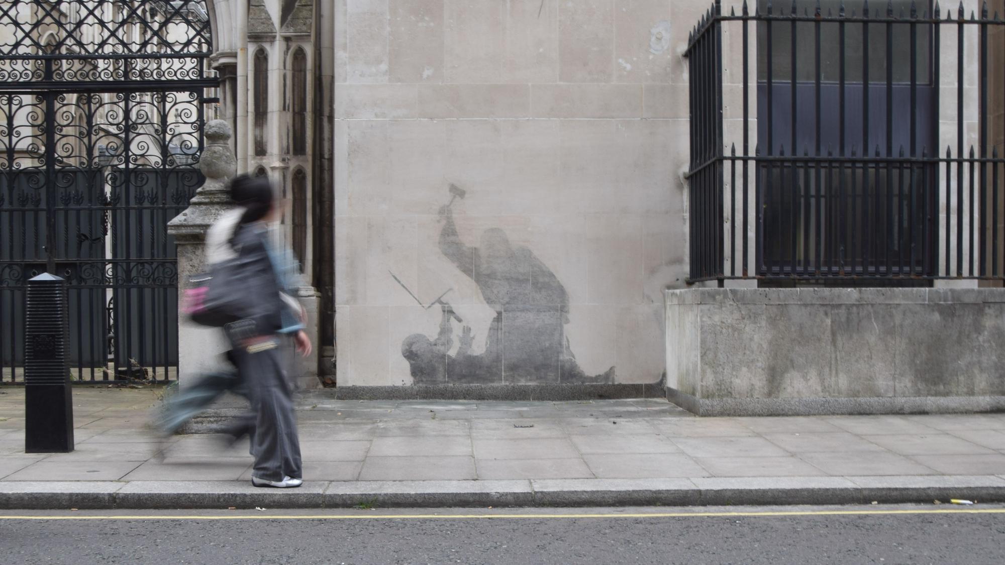 Menschen gehen an dem neuesten Kunstwerk des britischen Künstlers Banksy an den Royal Courts of Justice vorbei. Das Werk wurde teilweise schon wieder entfernt.