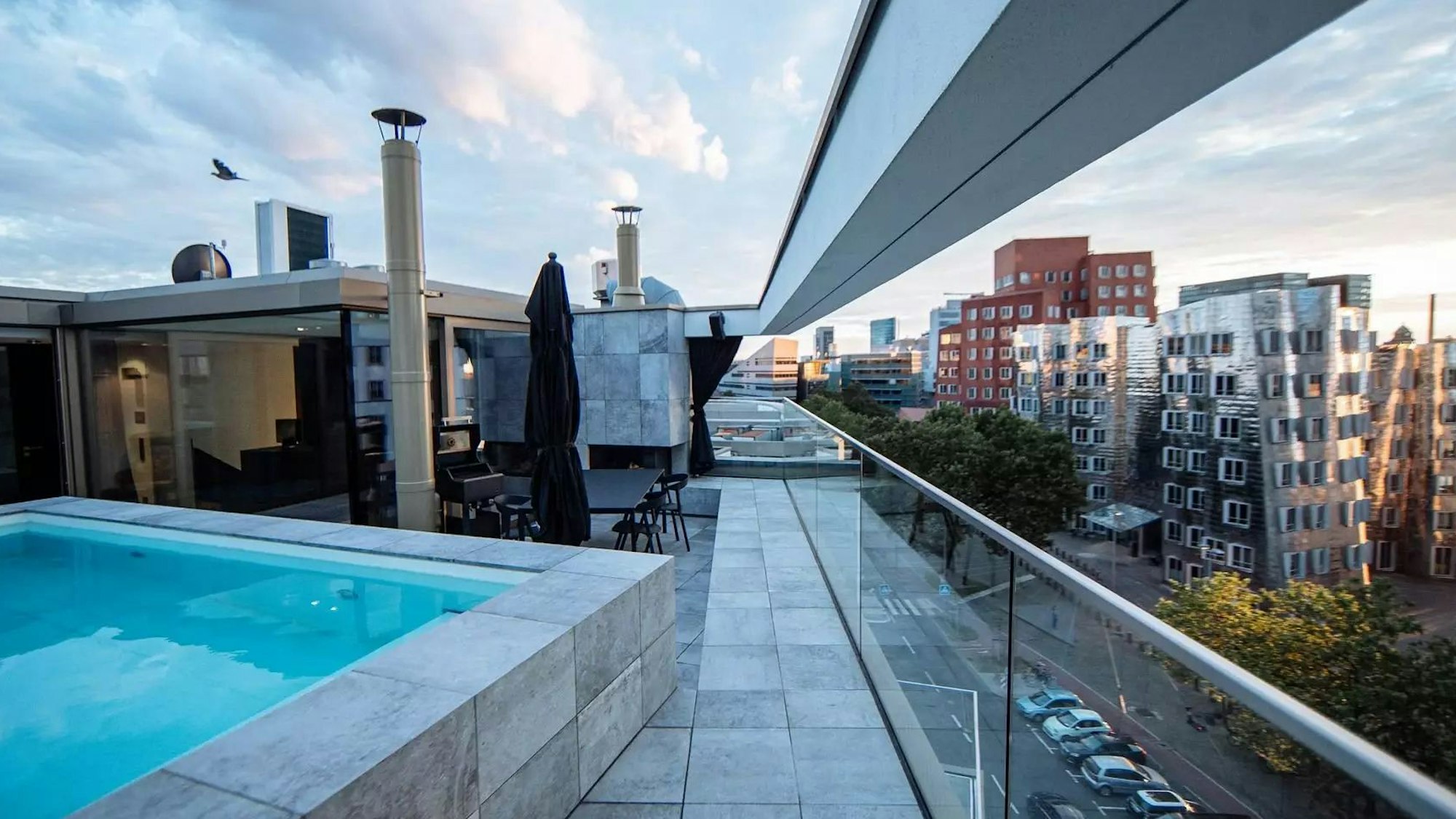 Blick auf die Dachterrasse der Luxuswohnung in Düsseldorf mit Pool und Sitzgelegenheiten.