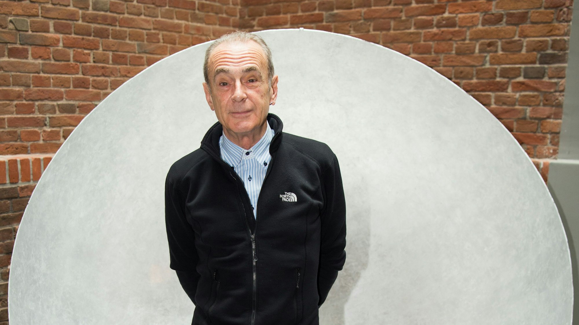 Der englische Sänger und Gitarrist Francis Rossi von der Band Status Quo steht in einem Gebäude vor einer Wand.