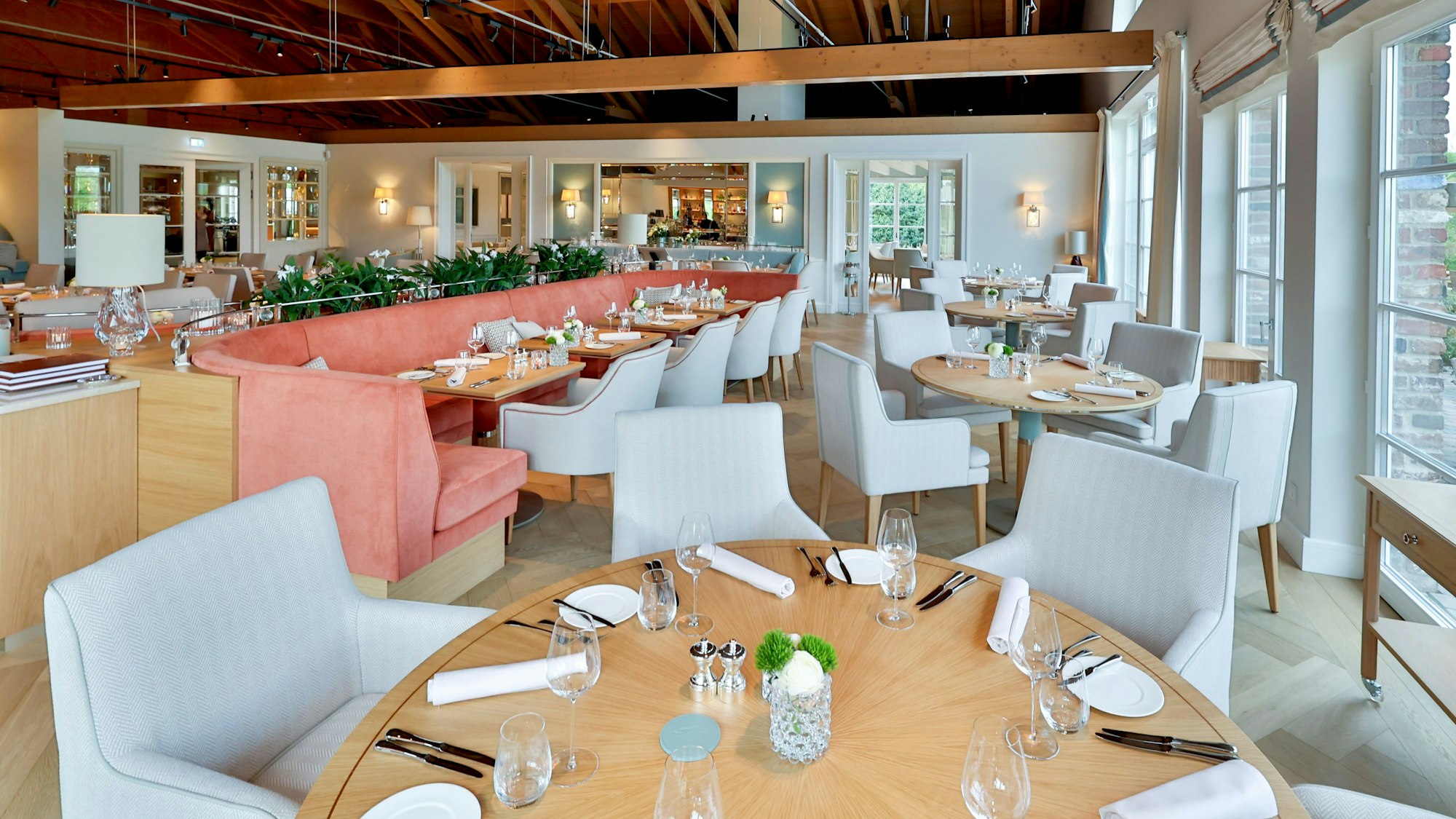 Der Gastraum ist zu sehen mit hellen Sesseln und Tischen in hellem Holz.